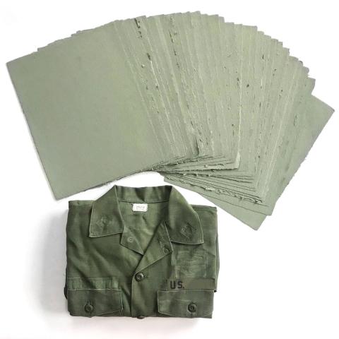 a stack of paper is fanned out above a folded military shirt